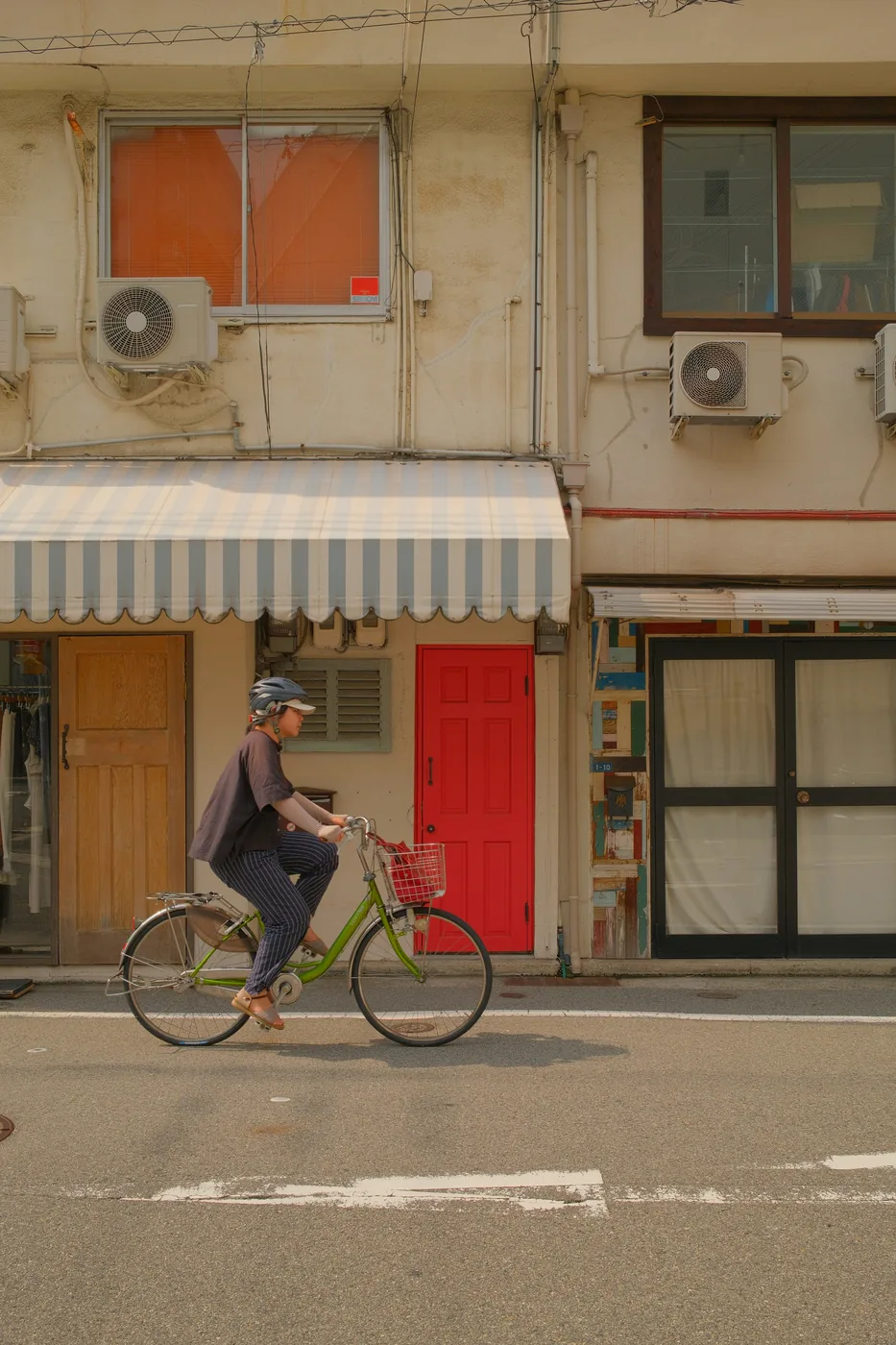 Cyclist on a lime bike past a cream building with a red door. Buried Treasure
