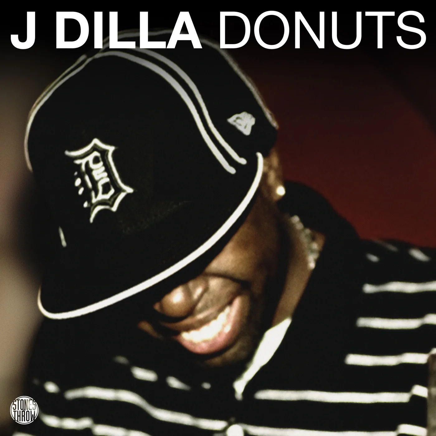 J Dilla Donuts album cover. smiling portrait in a Detroit D cap