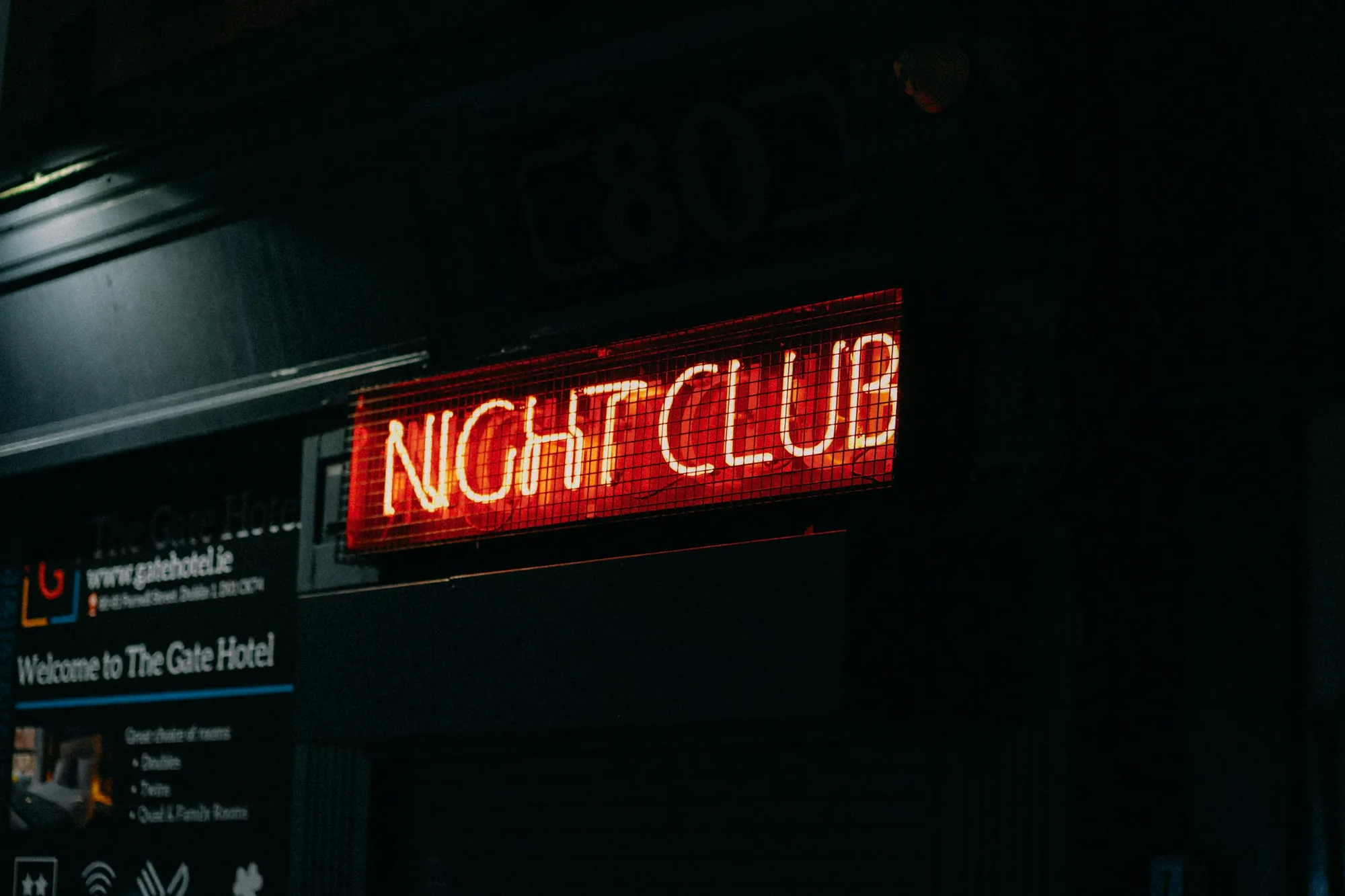 Flash-lit Kingsway warehouse door, photocopied flyer peeling off metal, parkas in a late-90s DIY queue